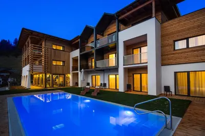 a house with a swimming pool in front of it at Mölgg Dolomites Residence in San Vigilio Di Marebbe