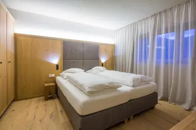 a large bed in a room with a large window at Mölgg Dolomites Residence in San Vigilio Di Marebbe