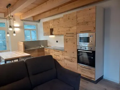 a living room with a couch and a kitchen at Mansarda Vale e Schena con vasca idromassaggio 4 posti letto a Cortina d'Ampezzo in San Vito di Cadore