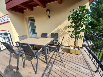 a patio with a table and chairs on a deck at Mansarda Vale e Schena con vasca idromassaggio 4 posti letto a Cortina d'Ampezzo in San Vito di Cadore