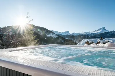 a jacuzzi tub with mountains in the background at Hotel Ciurnadú in La Valle