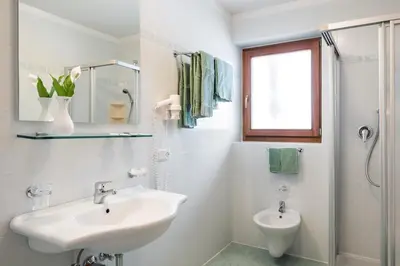 a white bathroom with a sink and a shower at Hotel Ciurnadú in La Valle