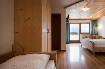 a bedroom with two beds and a wooden wall at Hotel Ciurnadú in La Valle