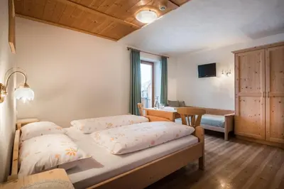 a bedroom with two beds and a desk in it at Hotel Ciurnadú in La Valle