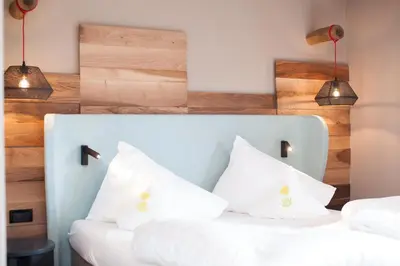 two white pillows on a bed with two lights at Örtlerhof in Tirolo