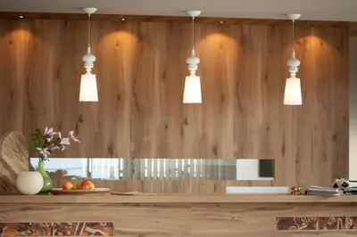 a kitchen with wooden walls and three pendant lights at Örtlerhof in Tirolo
