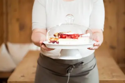 a woman holding a plate with a dessert in a glass dish at Örtlerhof in Tirolo