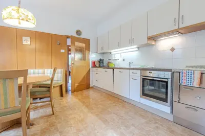 a kitchen with white cabinets and a table and a dining room at Haus Vieider in Collepietra