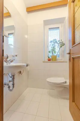 a white bathroom with a sink and a toilet at Haus Vieider in Collepietra