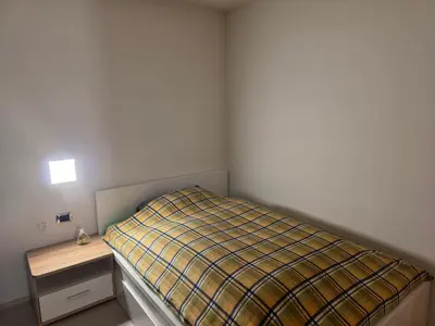 a small bedroom with a bed and a night stand at V91 Young People Citymountain in Brunico