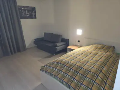 a bedroom with a bed and a blue chair at V91 Young People Citymountain in Brunico