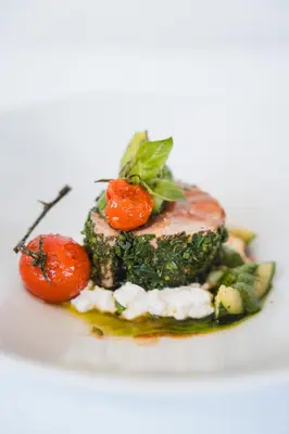 a plate of food with broccoli and tomatoes on it at Apartments Clivus in Corvara in Badia