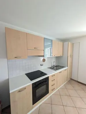 a kitchen with wooden cabinets and a sink and a stove at Comodità in centro a Tesero in Tesero