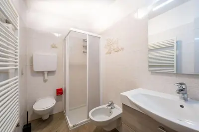 a white bathroom with a toilet and a sink at Cesa de Piè in Canazei