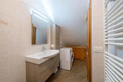 a bathroom with a sink and a washer and dryer at Cesa de Piè in Canazei