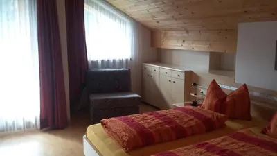 a bedroom with a bed and a chair at Roanerhof in San Genesio Atesino
