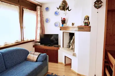 a living room with a blue couch and a fireplace at Villa Antermont in Canazei