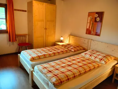 a bedroom with two beds and a red chair at Huberhof Abendsonne in Terento