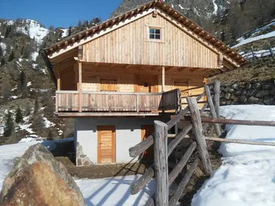 a wooden cabin with a balcony in the snow at Huberhof Abendsonne in Terento