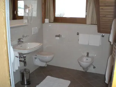 a white bathroom with a toilet and a sink at Huberhof Abendsonne in Terento