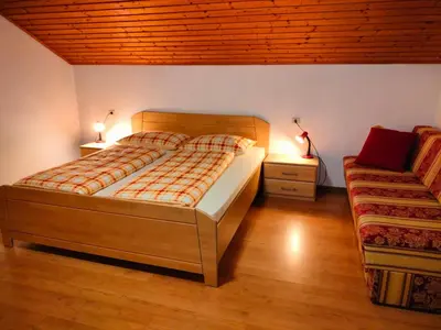 a bedroom with a large bed and a couch at Huberhof Abendsonne in Terento