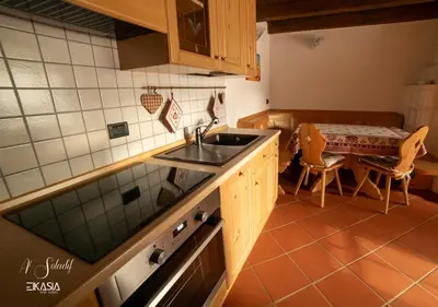 a kitchen with a sink and a table with chairs at Al Soladif - Mansarda con vista in Cavalese