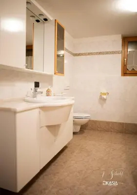 a white bathroom with a sink and a toilet at Al Soladif - Mansarda con vista in Cavalese