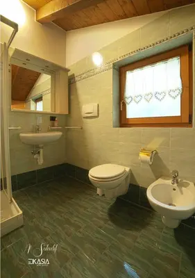 a bathroom with a sink and a toilet and a window at Al Soladif - Mansarda con vista in Cavalese