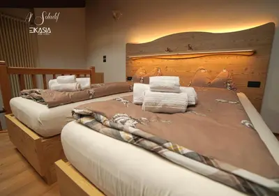 two large beds in a room with a large headboard at Al Soladif - Mansarda con vista in Cavalese