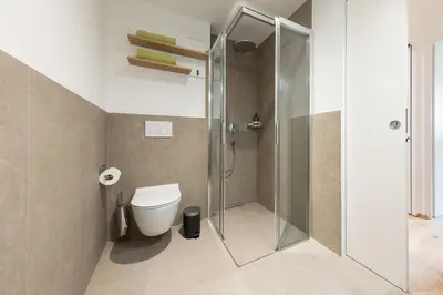 a bathroom with a toilet and a glass shower at Kati`s Guesthouse-Zentral in Kaltern in Caldaro