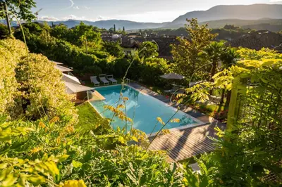an image of a swimming pool in a garden with trees at Kati`s Guesthouse-Zentral in Kaltern in Caldaro