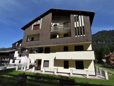 a building in the snow with mountains in the background at Apartment Apt 18 by Interhome in Campitello di Fassa
