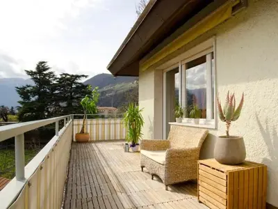 a balcony with a chair and a table and a window at Apartment Vicolo Sabbia in Bolzano