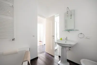 a white bathroom with a sink and a mirror at Apartment Vicolo Sabbia in Bolzano