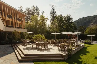 a patio with tables and chairs and umbrellas at Taubers Bio Vitalhotel in Chienes