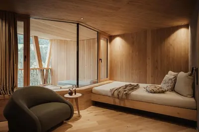 a bedroom with a bed and a chair and a window at Taubers Bio Vitalhotel in Chienes