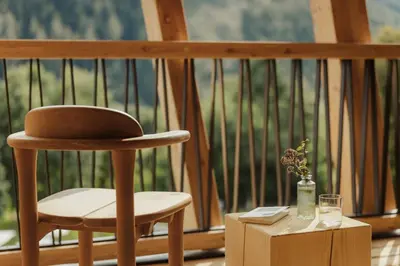 a wooden chair sitting on a porch with a glass of water at Taubers Bio Vitalhotel in Chienes