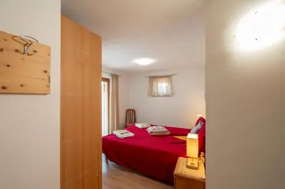 a bedroom with a red bed with a red blanket at B&B Casa Nadia in Tesero
