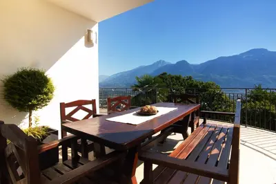 a wooden table and chairs on a balcony with mountains at Residence Untermösslhof - La Villa in Lana