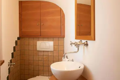 a bathroom with a toilet and a sink and a cabinet at Residence Untermösslhof - La Villa in Lana