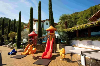 a playground with a slide and play equipment on a deck at Residence Untermösslhof - La Villa in Lana