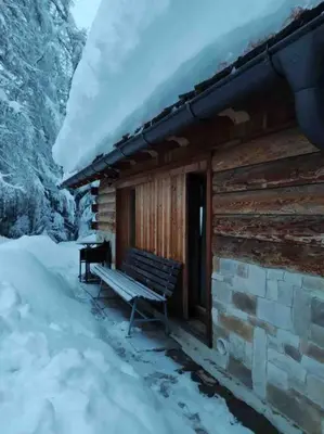 a bench sitting outside of a cabin in the snow at LA VOCE DEL BOSCO Selva di Cadore in Selva di Cadore