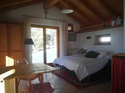a bedroom with a bed and a table and a window at LA VOCE DEL BOSCO Selva di Cadore in Selva di Cadore