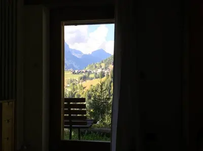 a window with a view of a bench and mountains at LA VOCE DEL BOSCO Selva di Cadore in Selva di Cadore