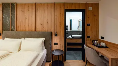 a bedroom with a bed and a bathroom with a sink at Dolomites Room and Breakfast Formiè in Vigo di Fassa