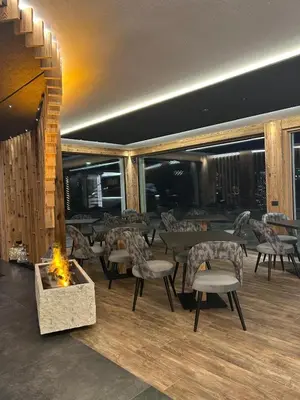 a restaurant with a fireplace and tables and chairs at Dolomites Room and Breakfast Formiè in Vigo di Fassa