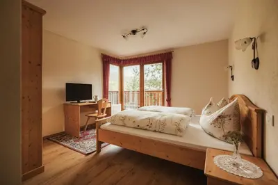 a bedroom with a bed and a desk with a television at Pension Torr in San Martino in Badia