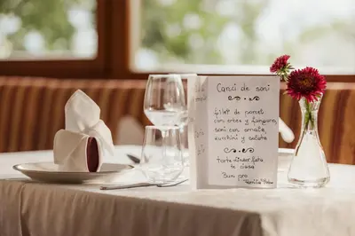 a table with a white table cloth with a wine glass at Pension Torr in San Martino in Badia