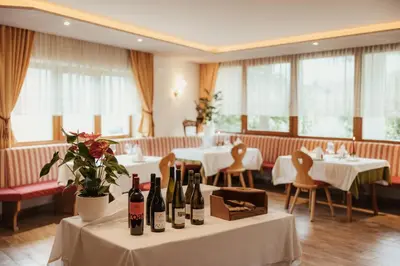 a restaurant with white tables and bottles of wine at Pension Torr in San Martino in Badia