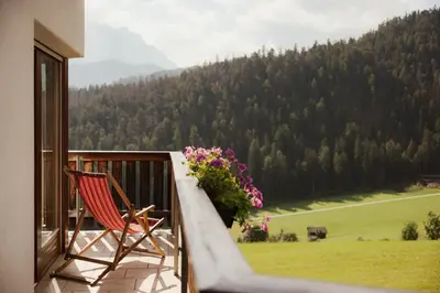 a rocking chair sitting on a balcony with a view at Pension Torr in San Martino in Badia